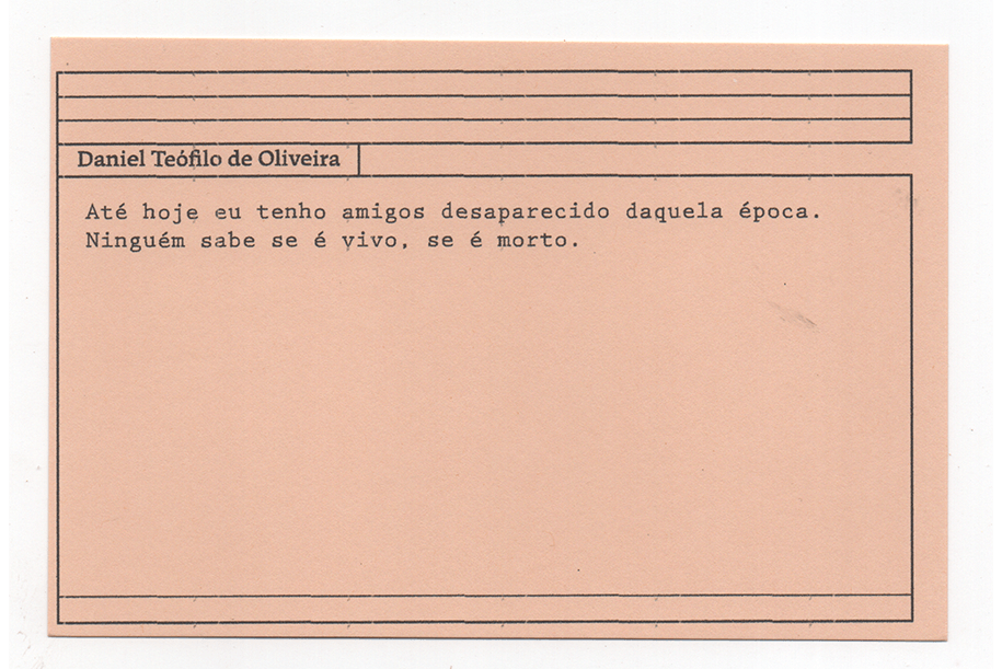 Fotografia de uma ficha horizontal cor de rosa claro com cinco pautas pretas na
parte superior. Abaixo delas, em letras pretas, o depoimento de Daniel Teófilo de
Oliveira, em letras pretas: “Até hoje eu tenho amigos desaparecido daquela época.
Ninguém sabe se é vivo, se é morto.” No rodapé, duas pautas pretas horizontais.