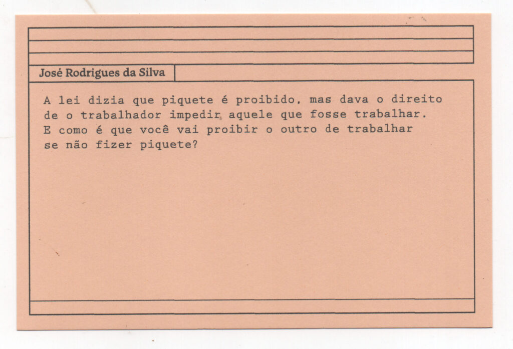 Fotografia de uma ficha horizontal cor de rosa claro com cinco pautas pretas na
parte superior. Abaixo delas, em letras pretas, o depoimento de José Rodrigues da
Silva”, em letras pretas: “A lei dizia que piquete é proibido, mas dava o direito de o
trabalhador impedir, aquele que fosse trabalhar. E como é que você vai proibir o
outro de trabalhar se não fizer piquete?” No rodapé, duas pautas pretas horizontais.
