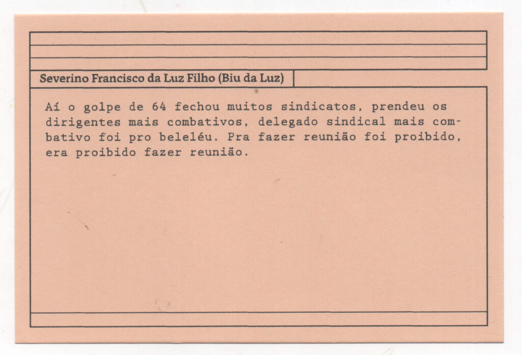 Fotografia de uma ficha horizontal cor de rosa claro com quatro pretas pautas na
parte superior. Em letras pretas o depoimento de Severino Francisco da Luz Filho
(Biu da Luz). “Aí o golpe de 64 fechou muitos sindicatos, prendeu os dirigentes mais
combativos, delegado sindical mais combativo foi pro beleléu. Pra fazer reunião foi
proibido, era proibido fazer reunião.” No rodapé, duas pautas pretas horizontais.